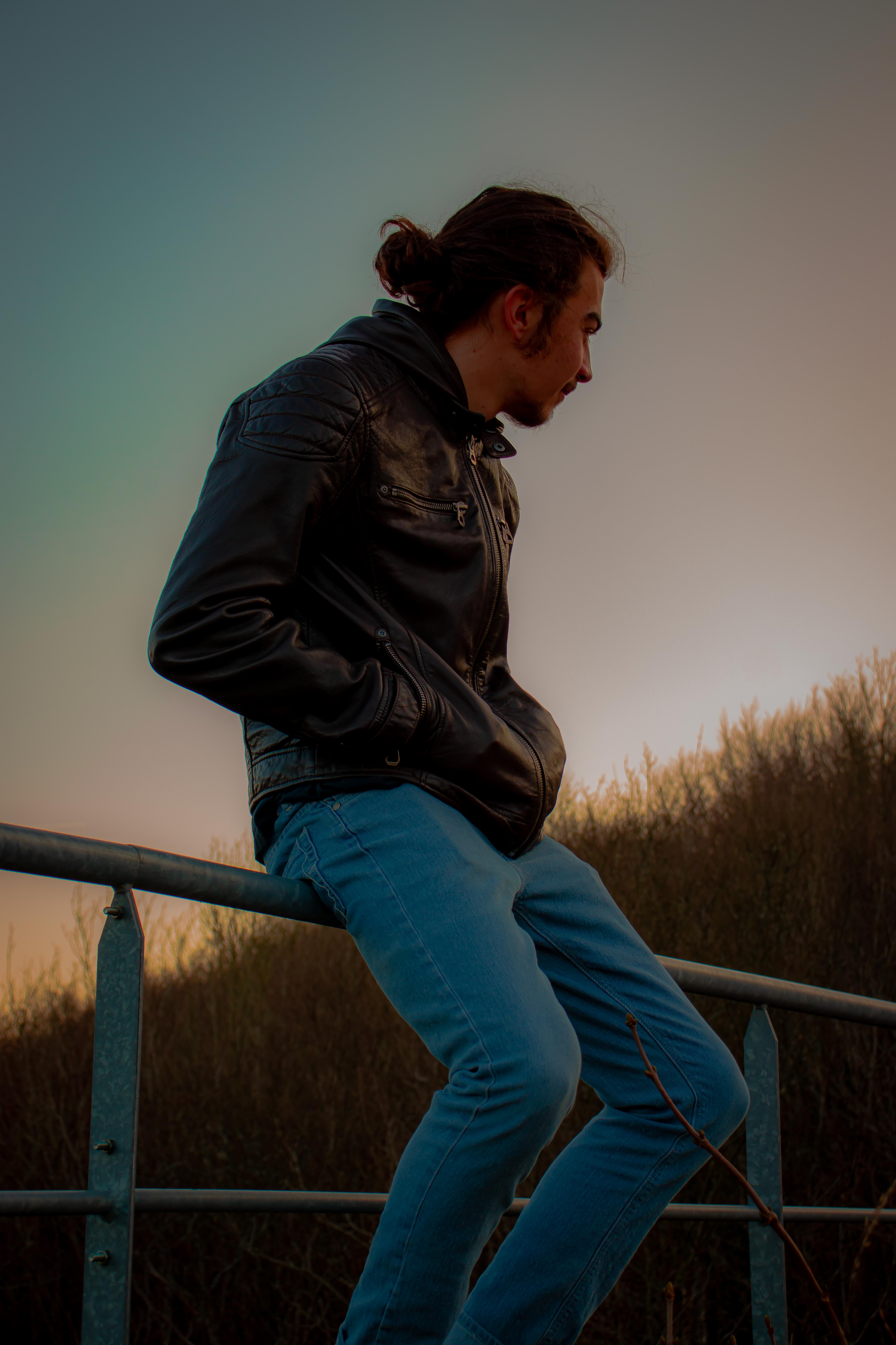 Photo d'un jeune homme assis sur une rambarde en métal